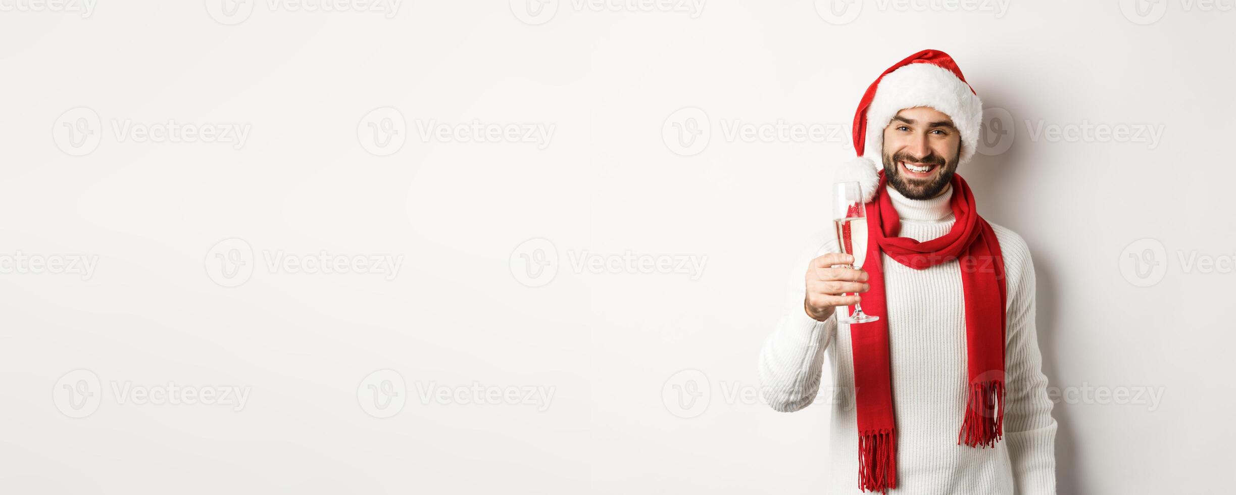 Christmas party and holidays concept. Handsome young man with beard, making a toast on New Year eve, holding glass of champagne and smiling, white background photo