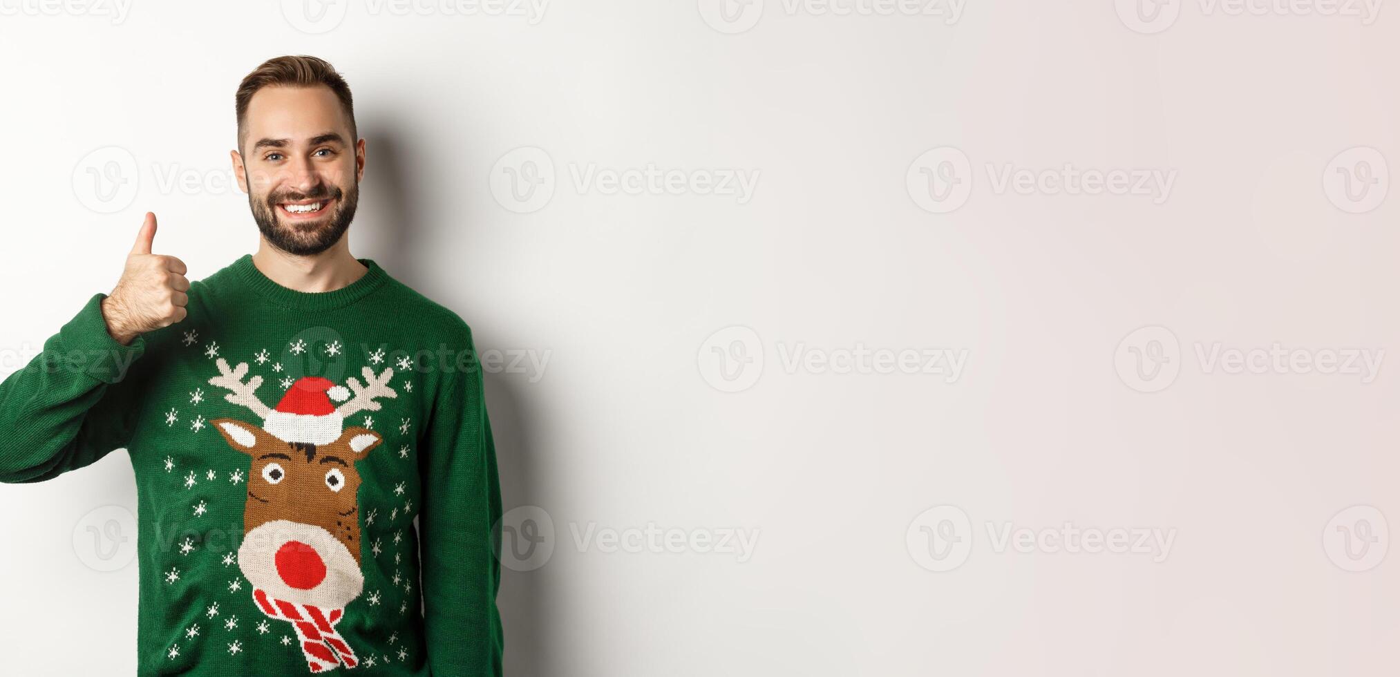 Winter holidays and christmas. Happy bearded man showing thumb up in approval, like something, praise good job, standing over white background photo