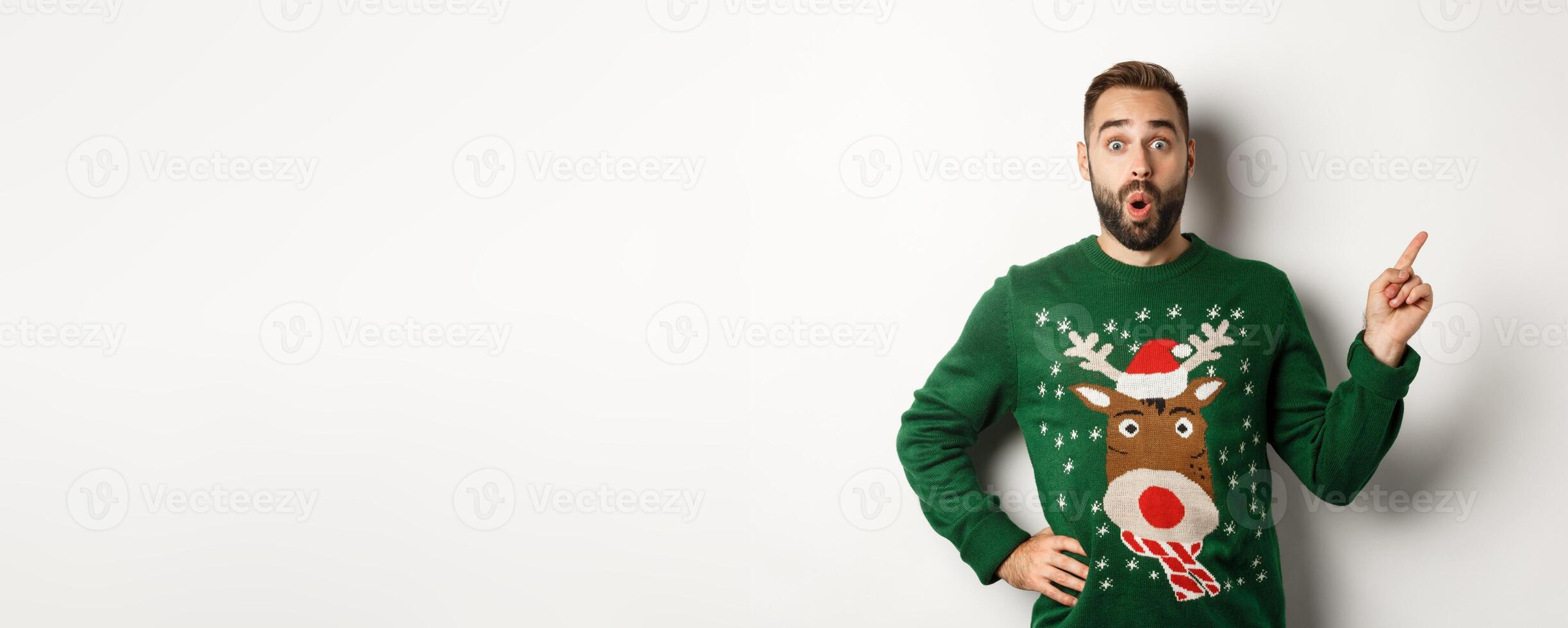 Winter holidays and christmas. Man looking excited as pointing finger right at logo, standing amazed against white background photo