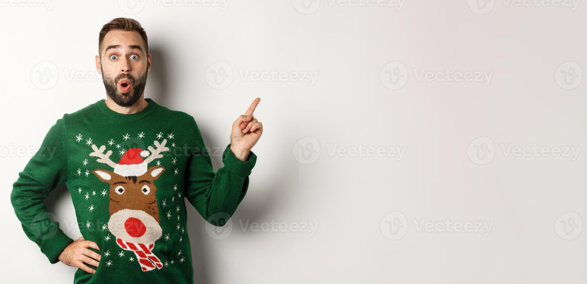 Winter holidays and christmas. Man looking excited as pointing finger right at logo, standing amazed against white background photo