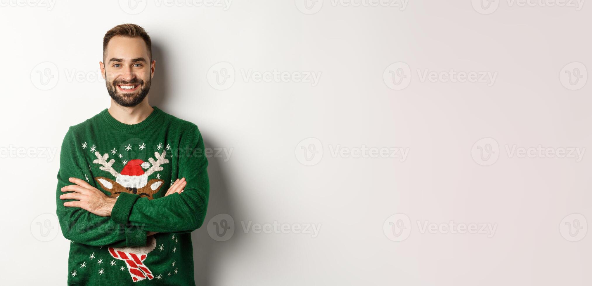 New Year party and winter holidays concept. Happy bearded man in funny christmas sweater standing against white background photo