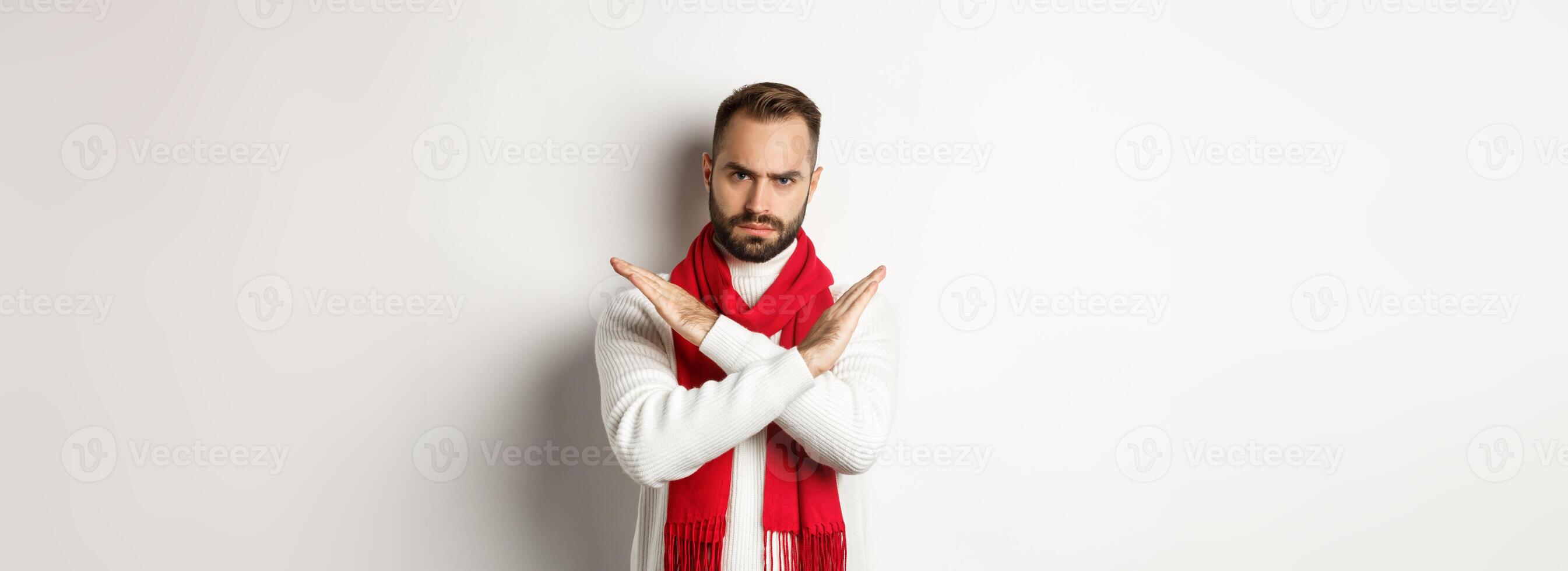 Angry bearded man frowning, showing cross stop gesture, telling no, forbid something bad, standing over white background photo