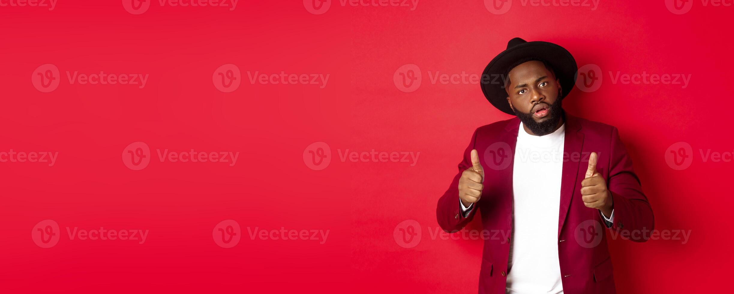 Impressed Black man saying good job, cheer up with thumbs-up, praise something, standing against red background photo