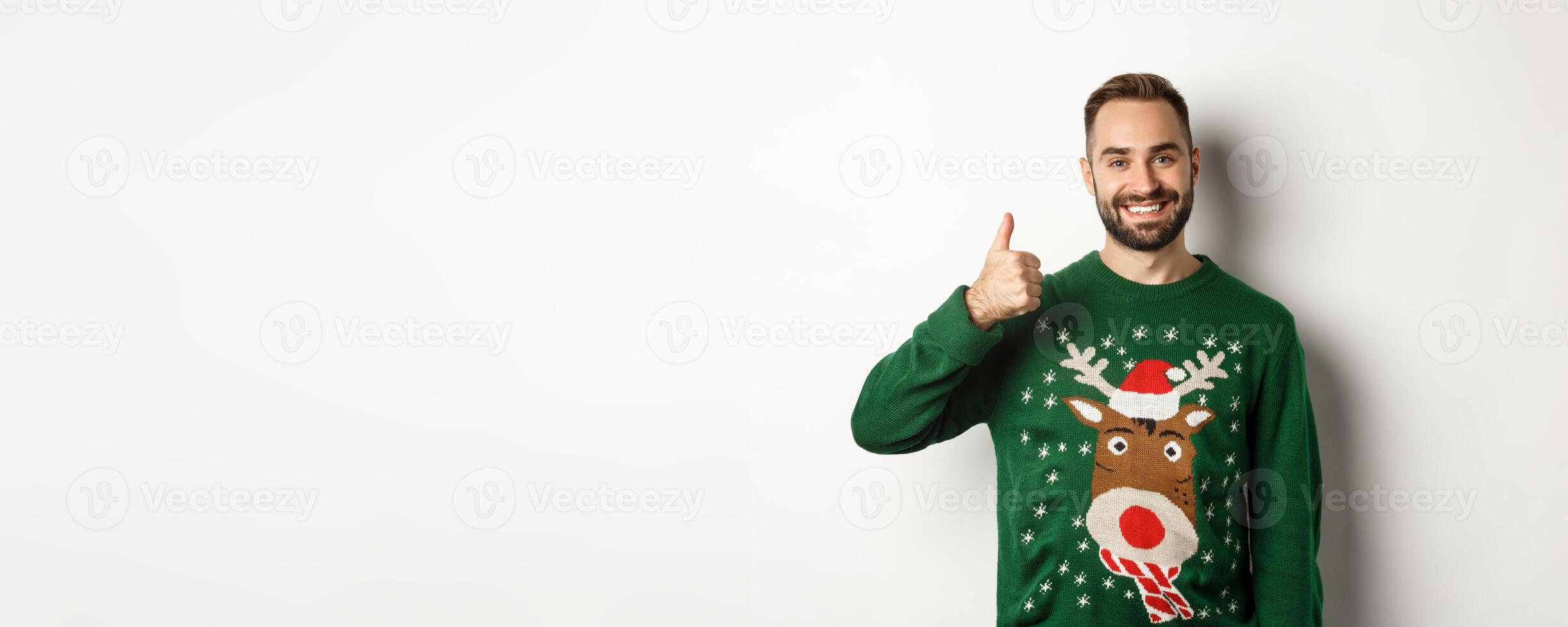 Winter holidays and christmas. Happy bearded man showing thumb up in approval, like something, praise good job, standing over white background photo