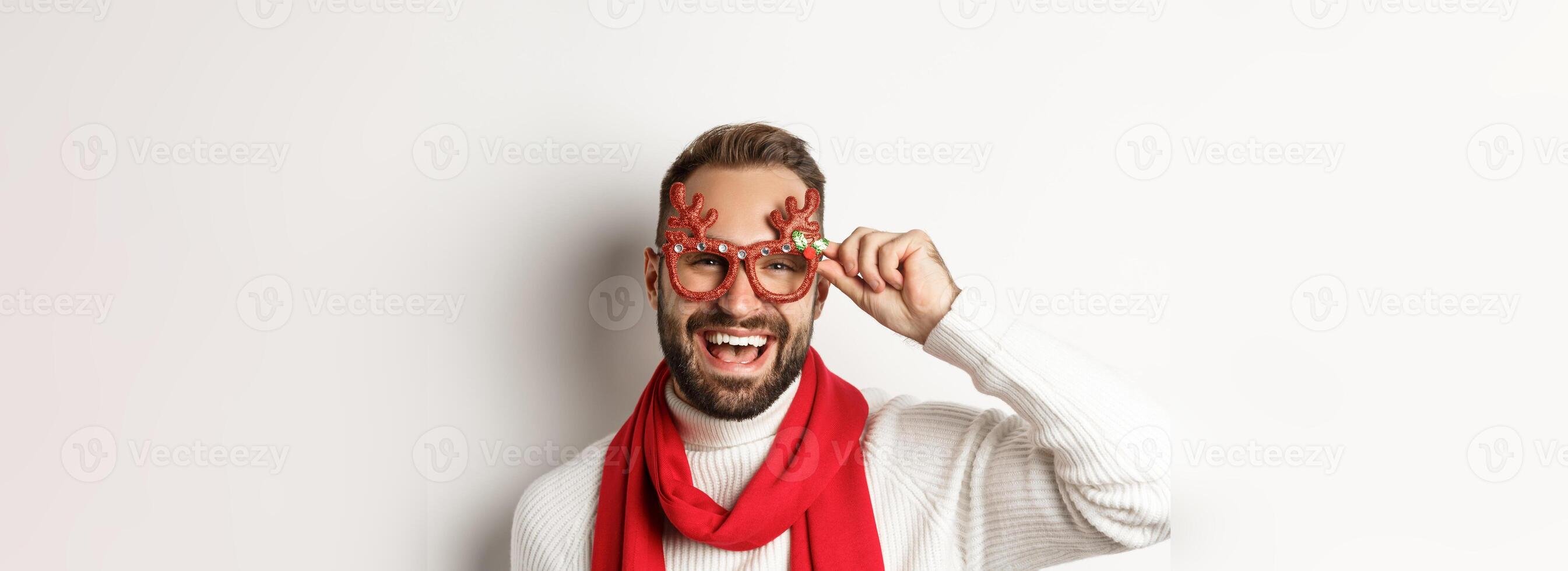 Christmas, New Year and celebration concept. Happy bearded guy in party glasses laughing and enjoying winter holidays, white background photo