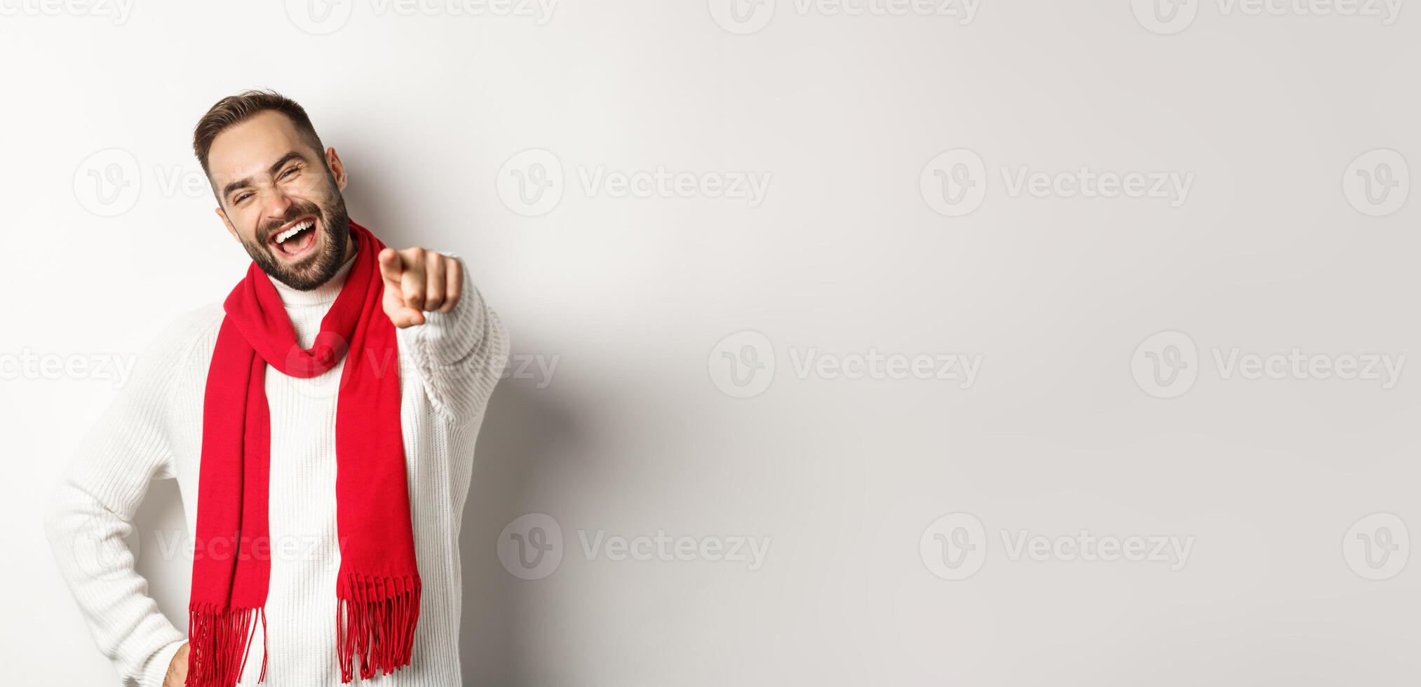 Winter holidays and shopping concept. Happy man wishing merry christmas and pointing at camera, need you, standing over white background photo