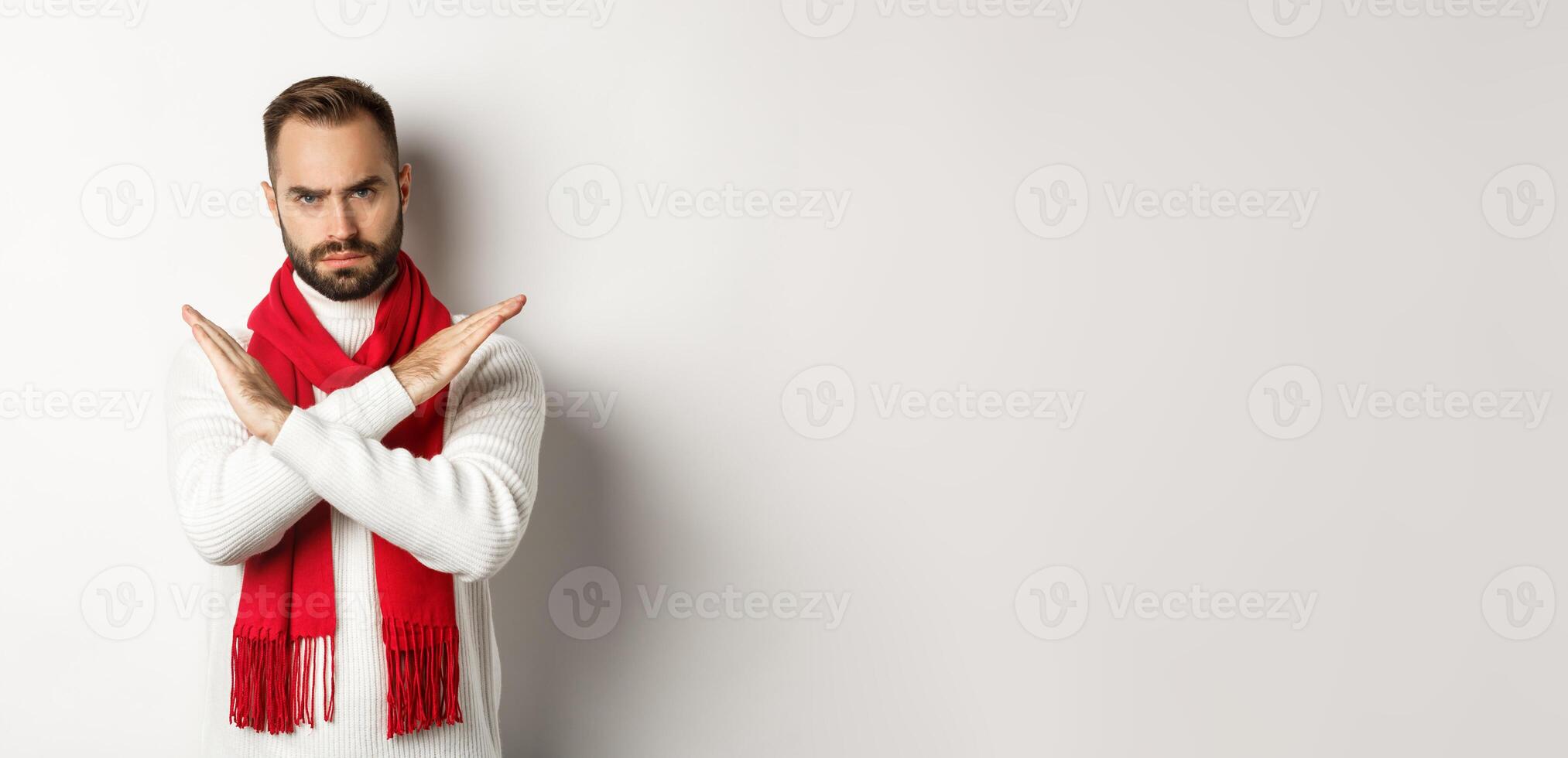 Angry bearded man frowning, showing cross stop gesture, telling no, forbid something bad, standing over white background photo