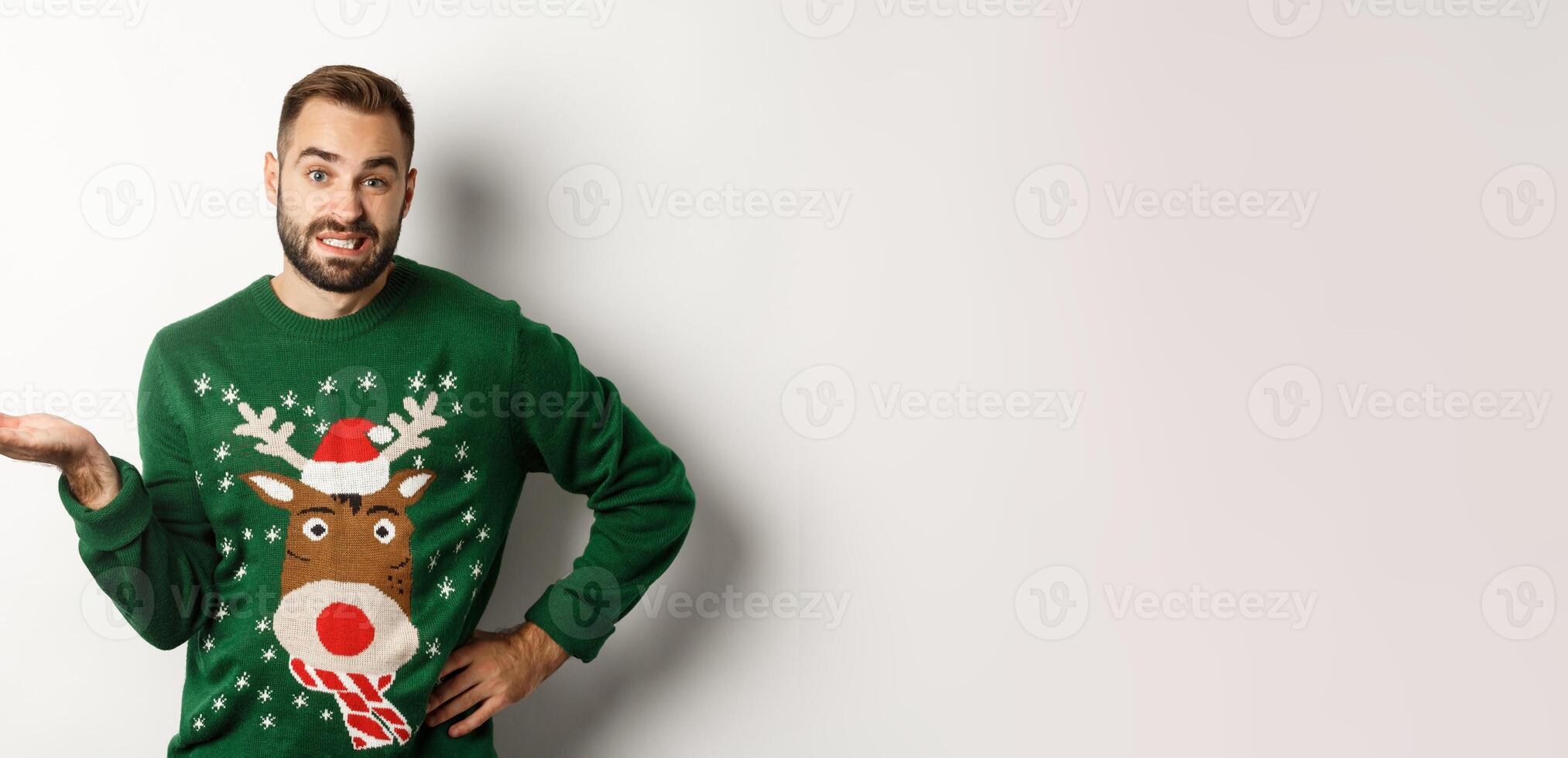New Year, holidays and celebration. Confused bearded guy in funny sweater, shrugging and looking clueless, dont know, looking awkward, standing over white background photo