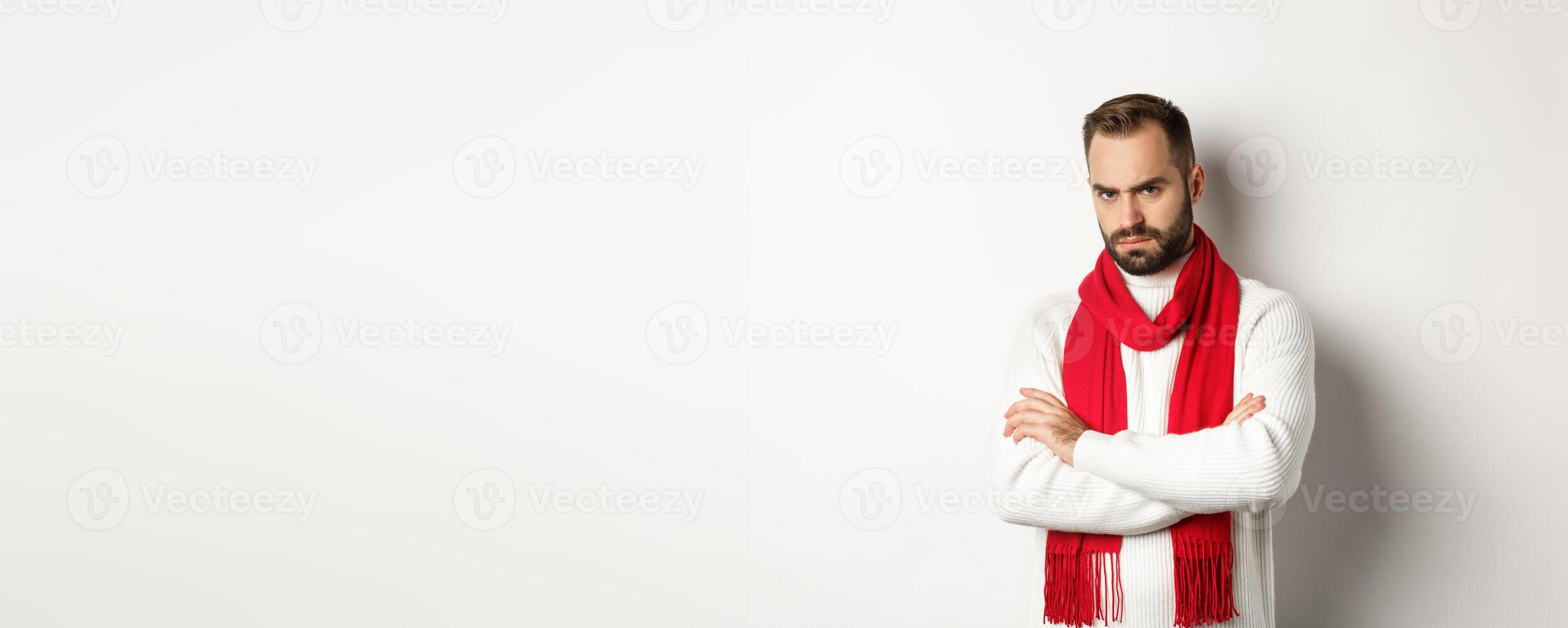 Bearded man looking angry and offended at you, cross arms on chest in defensive pose, sulking while standing in christmas sweater over white background photo