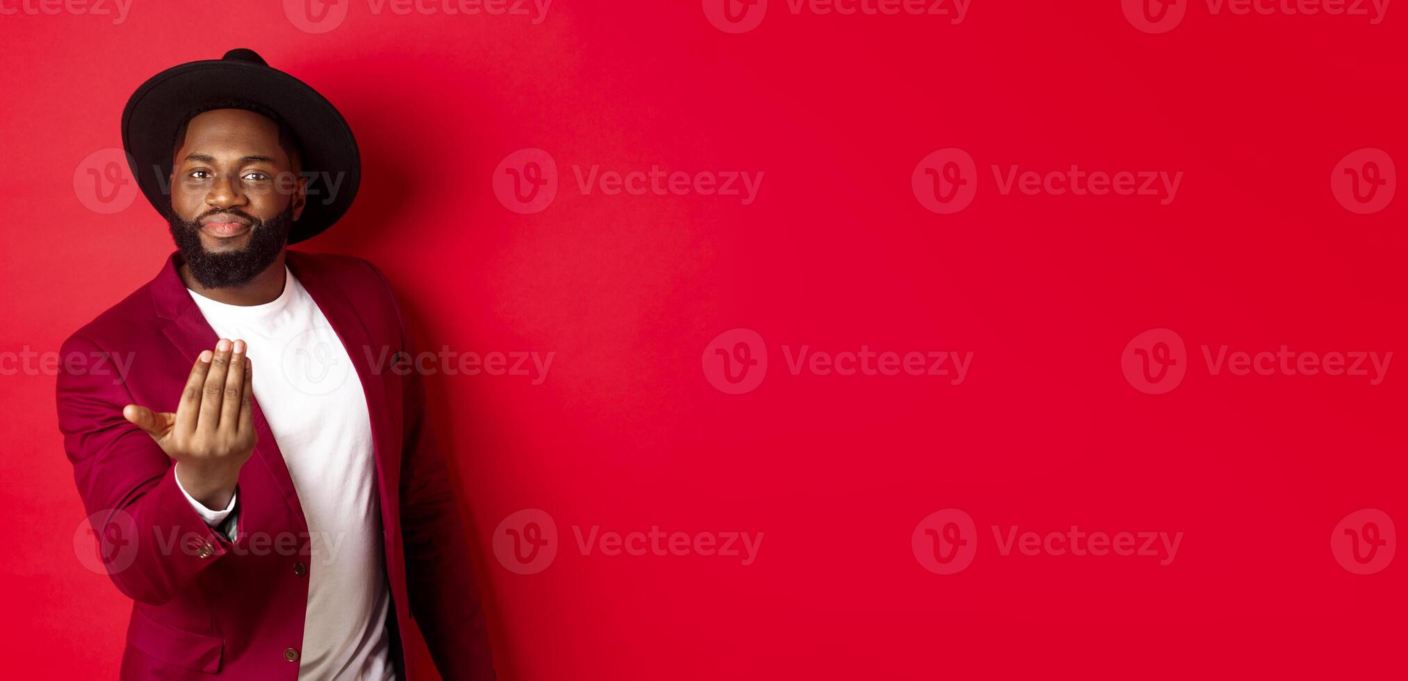 Handsome and masculine Black man asking come closer, luring to step forward, calling for you, standing over red background photo
