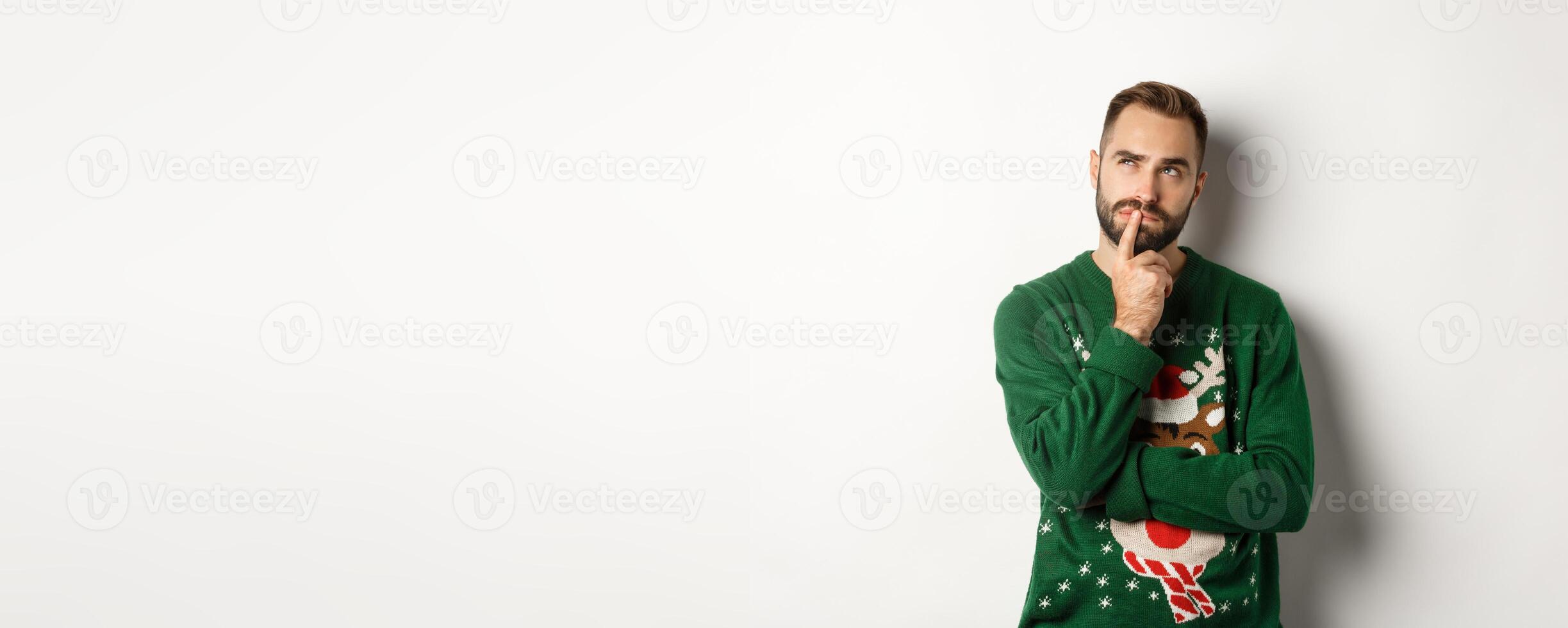 New year celebration and winter holidays concept. Handsome bearded man planning Christmas, thinking and looking at upper left corner, pondering gift ideas, white background photo