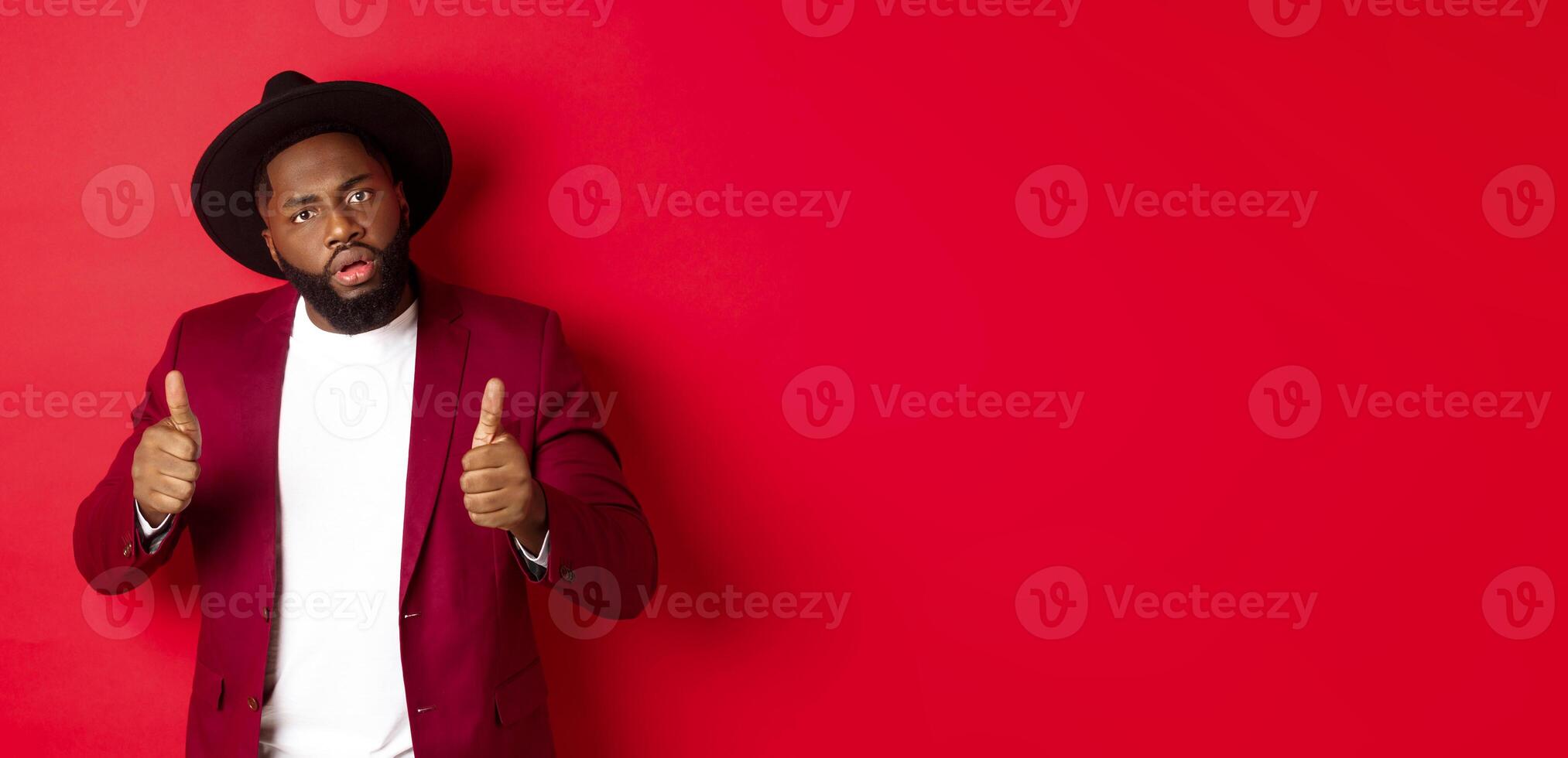Impressed Black man saying good job, cheer up with thumbs-up, praise something, standing against red background photo