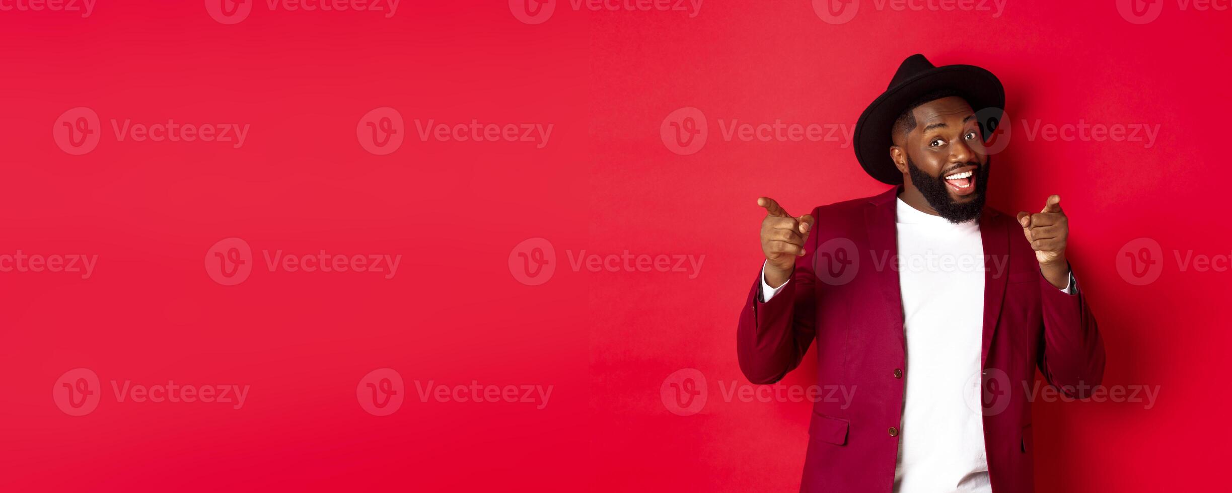 Christmas and people concept. Happy Black man celebrating New Year and dancing, wearing party outfit, red background photo