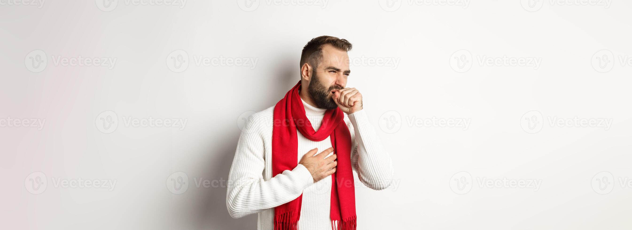 Christmas holidays and celebration concept. Man feeling sick, coughing and grimacing from sore throat, covid-19 symptoms at new year eve, standing over white background photo