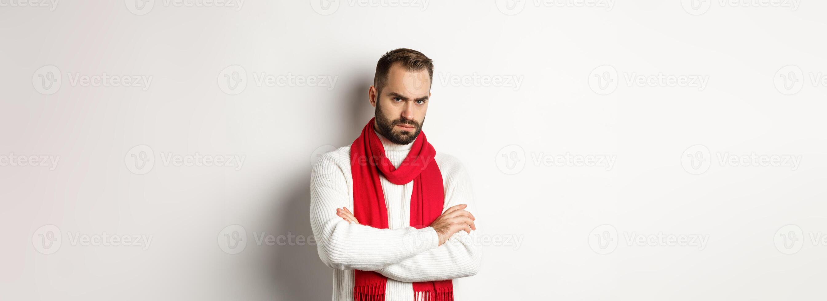 Bearded man looking angry and offended at you, cross arms on chest in defensive pose, sulking while standing in christmas sweater over white background photo