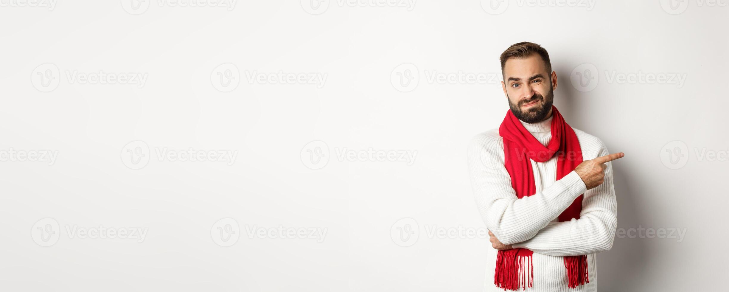 Christmas shopping and winter holidays concept. Displeased man pointing finger right and grimacing dissatisfied, standing skeptical against white background photo