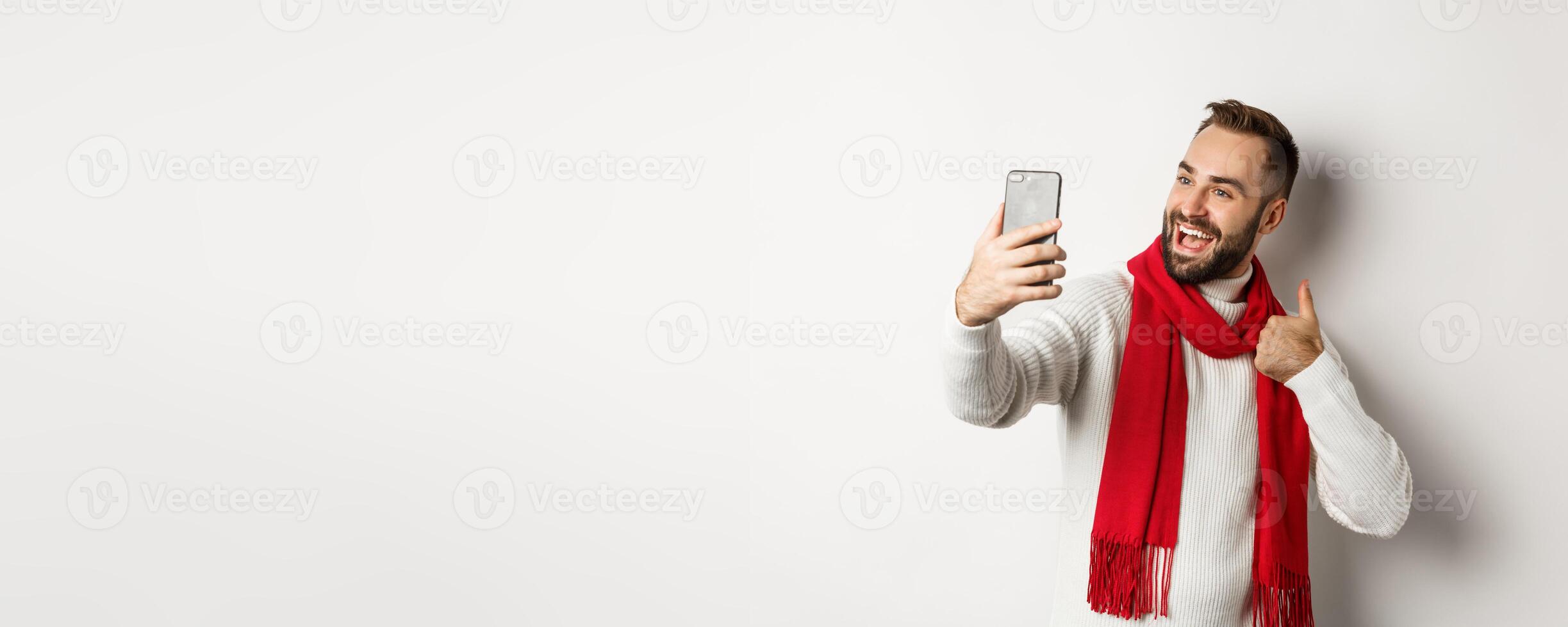 Happy bearded man call and showing thumbs up at mobile phone, like christmas gift, talking online, standing over white background photo