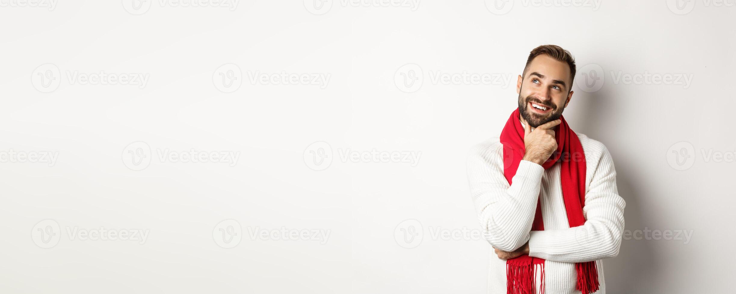 Christmas holidays and celebration concept. Thoughtful boyfriend thinking about gifts, looking at upper left corner and smiling satisfied, pondering new year ideas photo