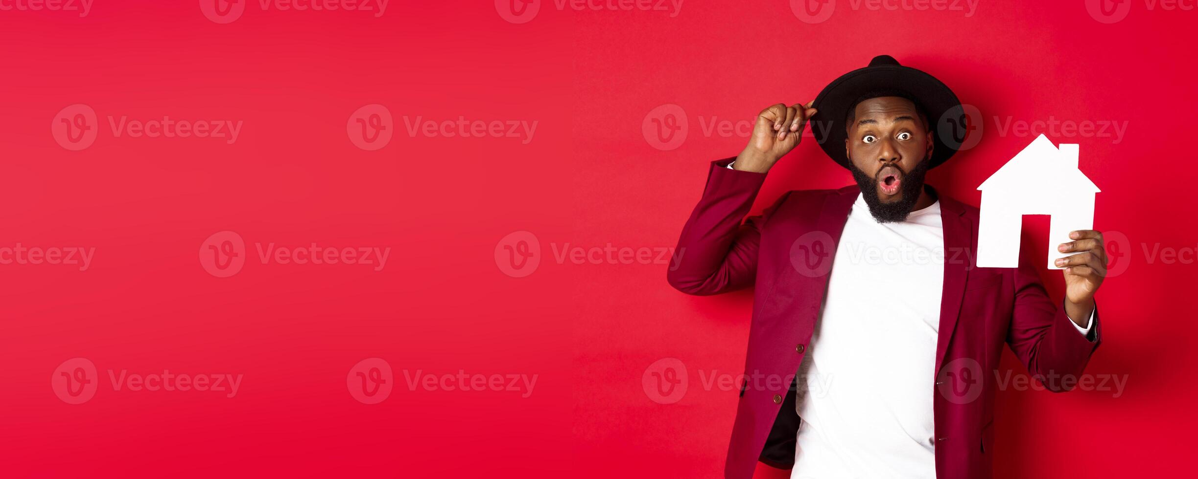 Real estate. Cheerful Black man showing paper house and smiling, recommending broker, standing over red background photo