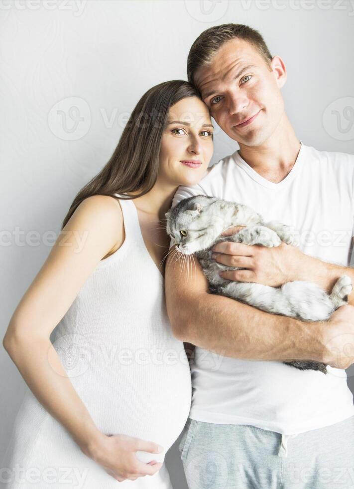 Young man with pregnant woman and cat indoors photo