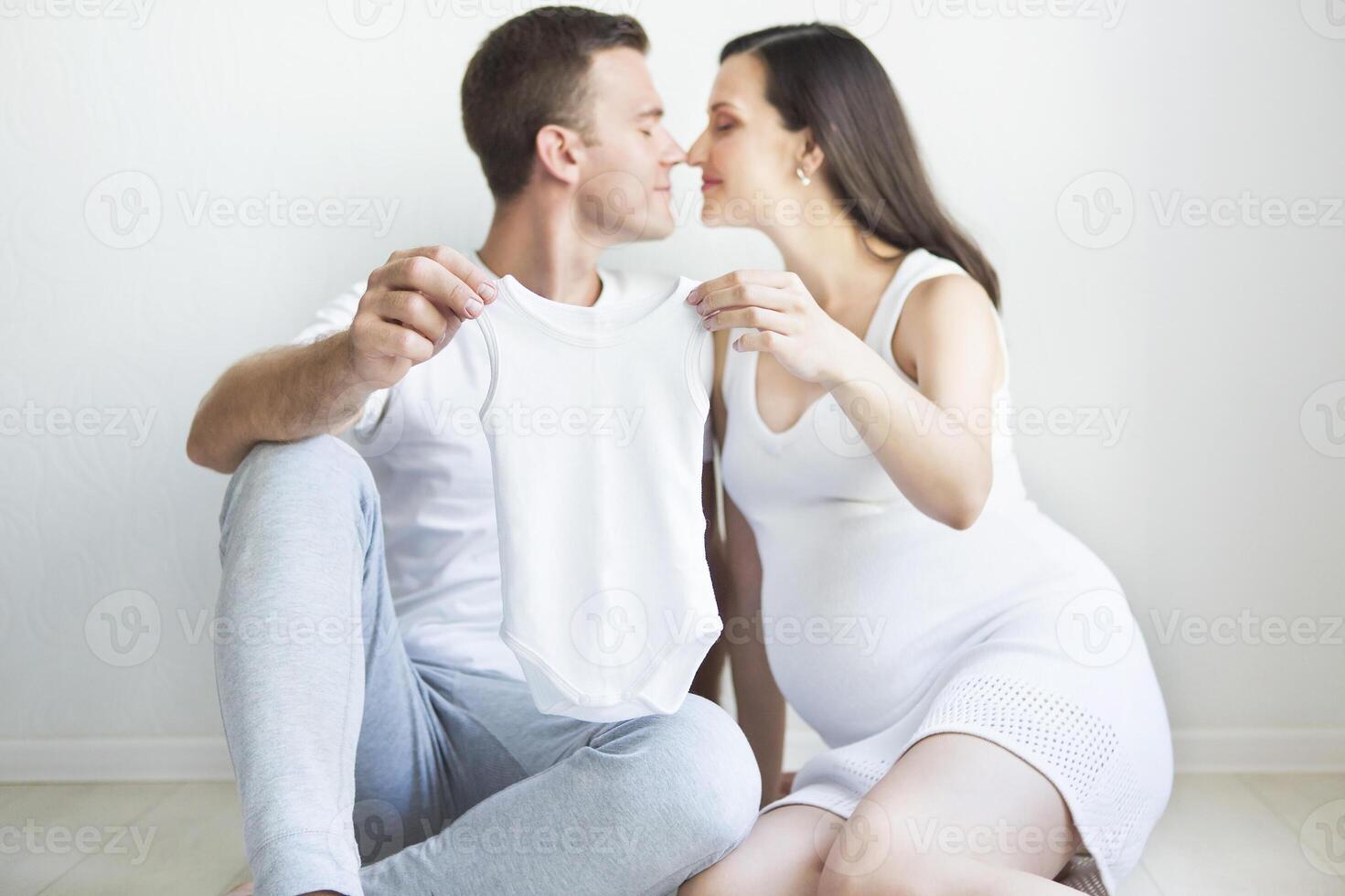 Young man and pretty pregnant woman with baby wear photo