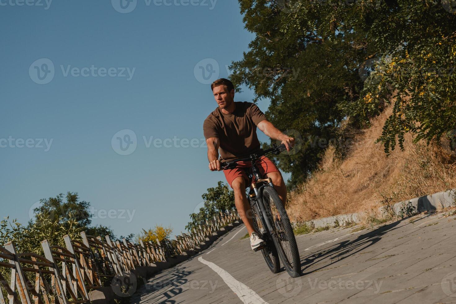 Confident young man riding bicycle by the scenic road outdoors photo