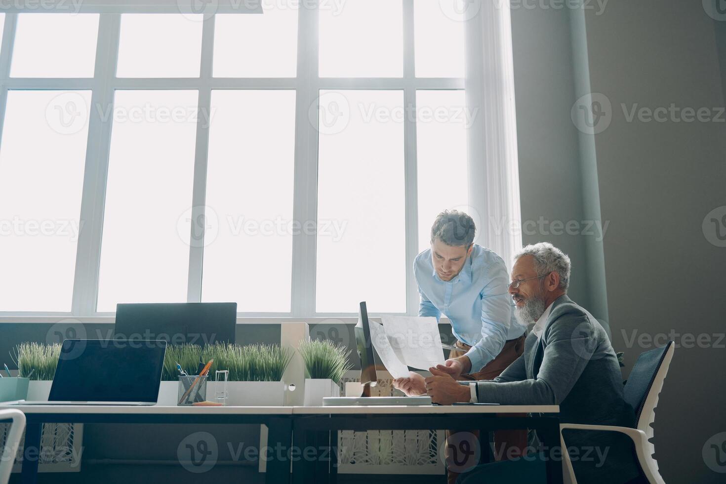 Two confident men going through documents while working in the office together photo