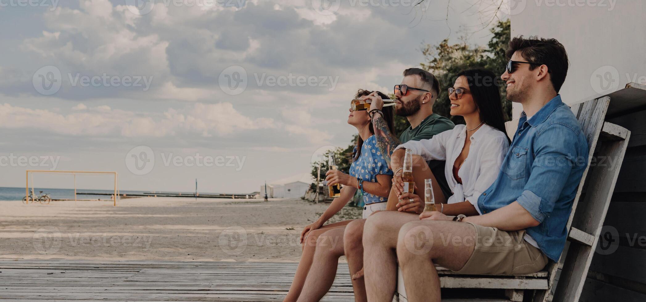 Group of joyful friends enjoying sea view while spending time near the beach house together photo