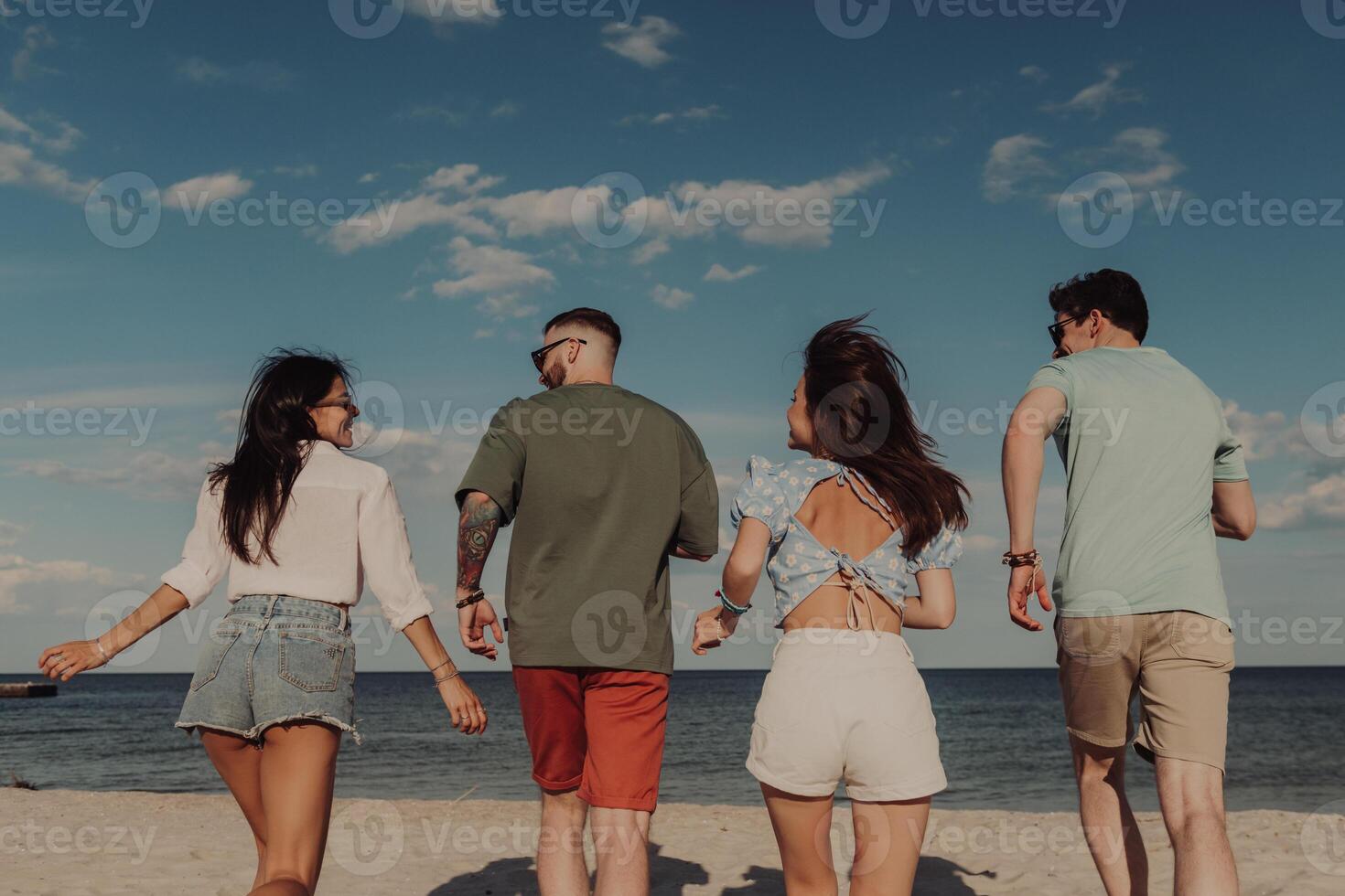 Rear view of happy young people running to the sea by the beach photo