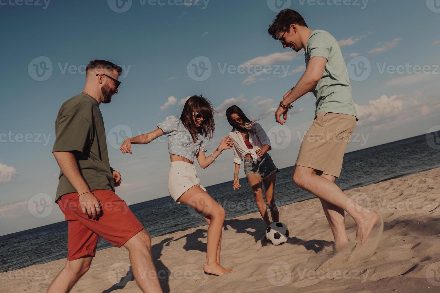 Group of happy young people spending fun time while playing soccer on the beach together photo