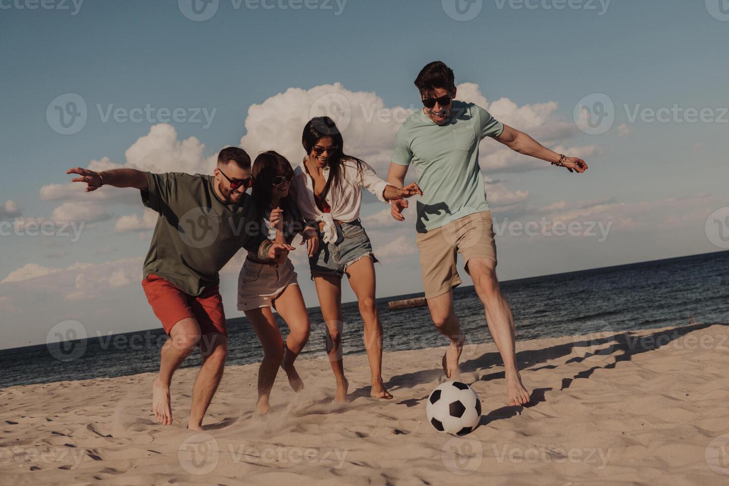 Group of young people playing soccer and having fun on the beach together photo