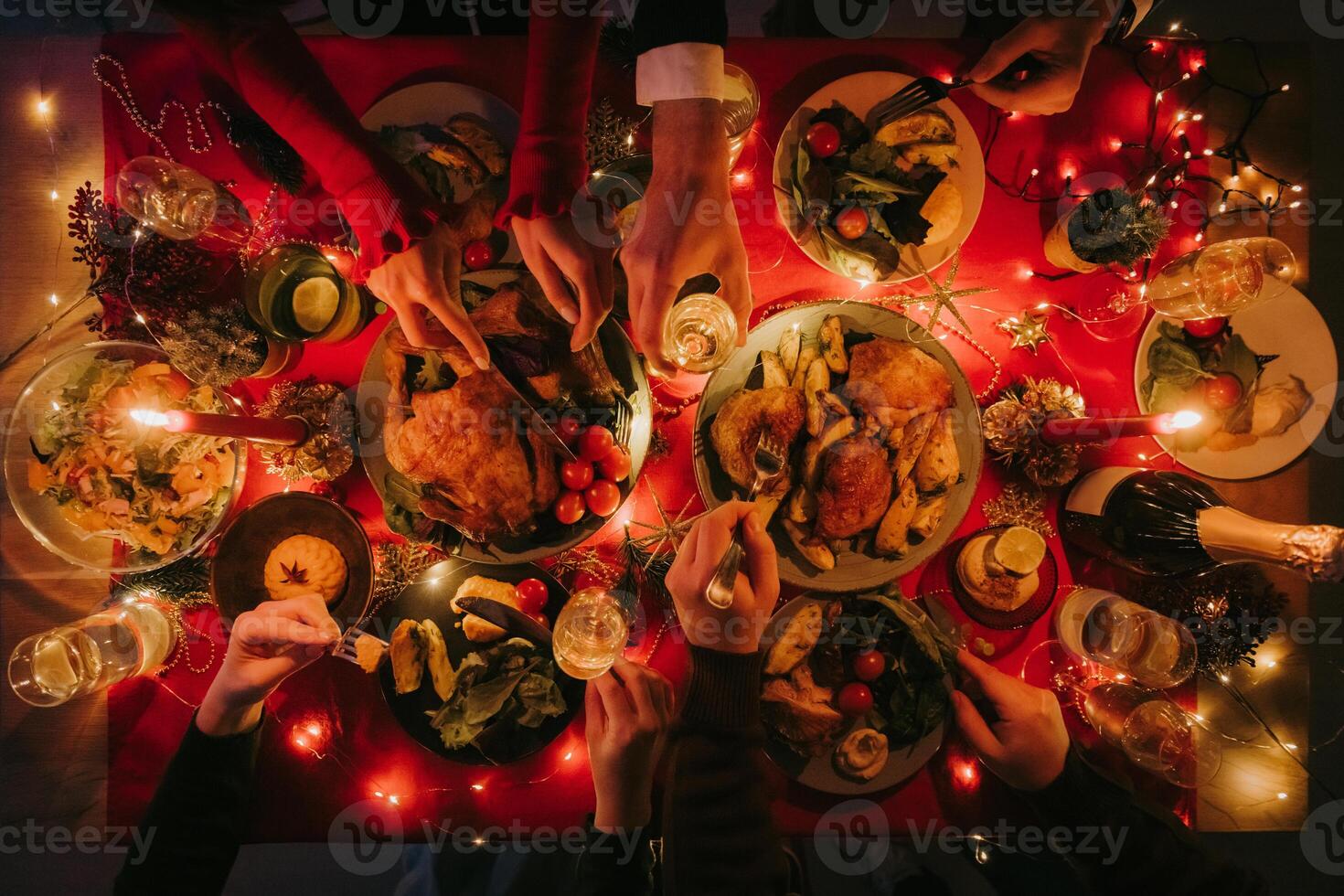 Top view of people enjoying variety of festive dishes while having Christmas dinner at the decorated table photo