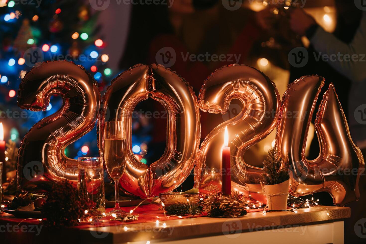 People celebrating New Year while golden balloons in shape of number 2024 laying on background photo