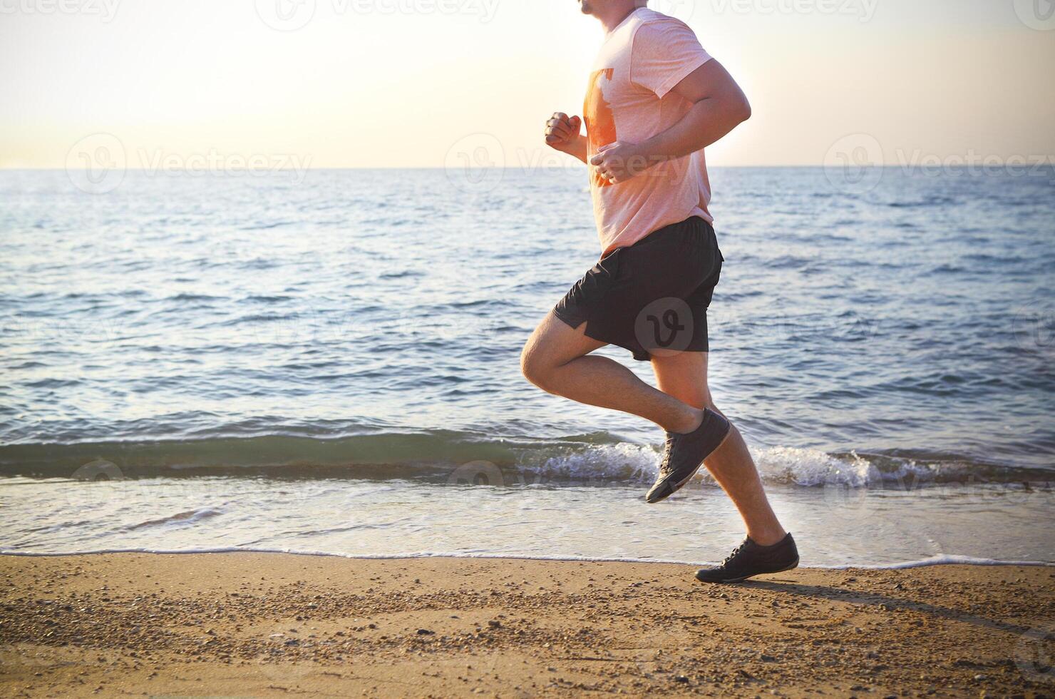 Man running on the beach at sunset photo