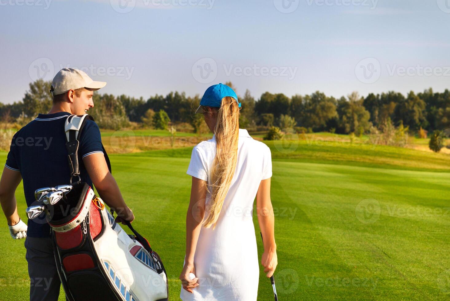 Sportive couple playing golf on a golf course walking to the next hole photo