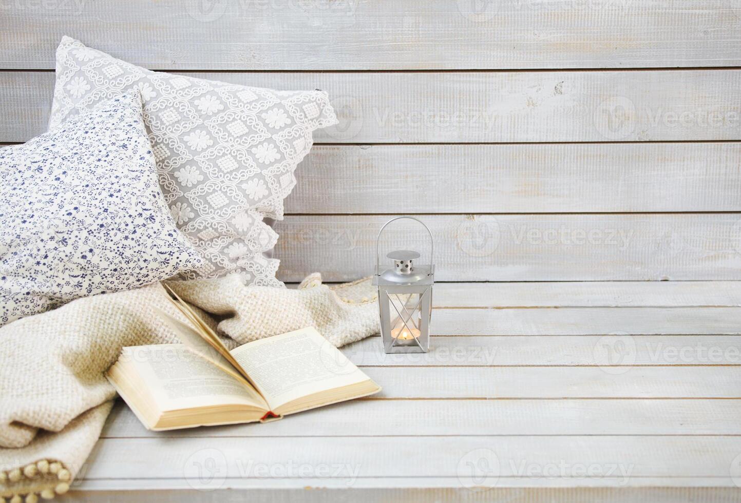 Cozy still life with lantern, pillows, book and plaid photo