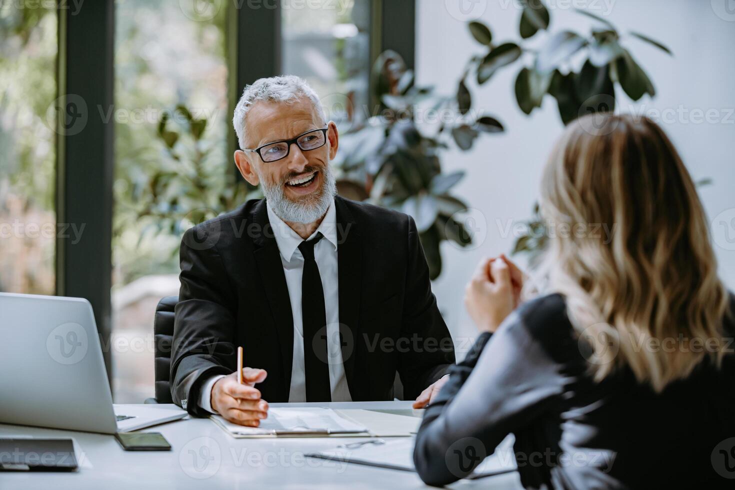 Happy mature man in formalwear having business meeting with employee in the modern office photo