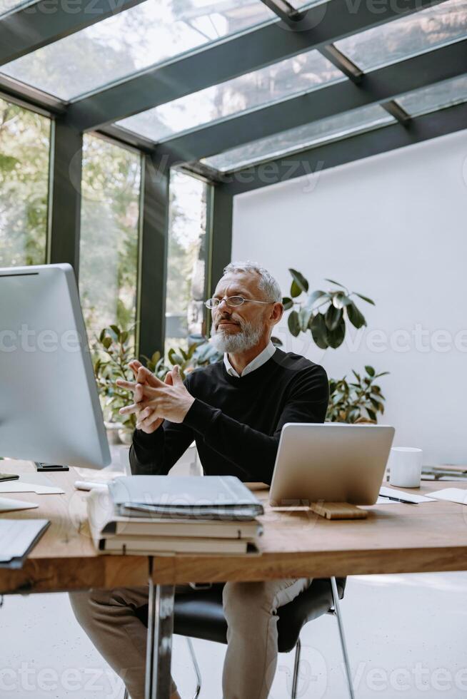 Confident mature man in smart casual wear looking at the computer while working in office photo
