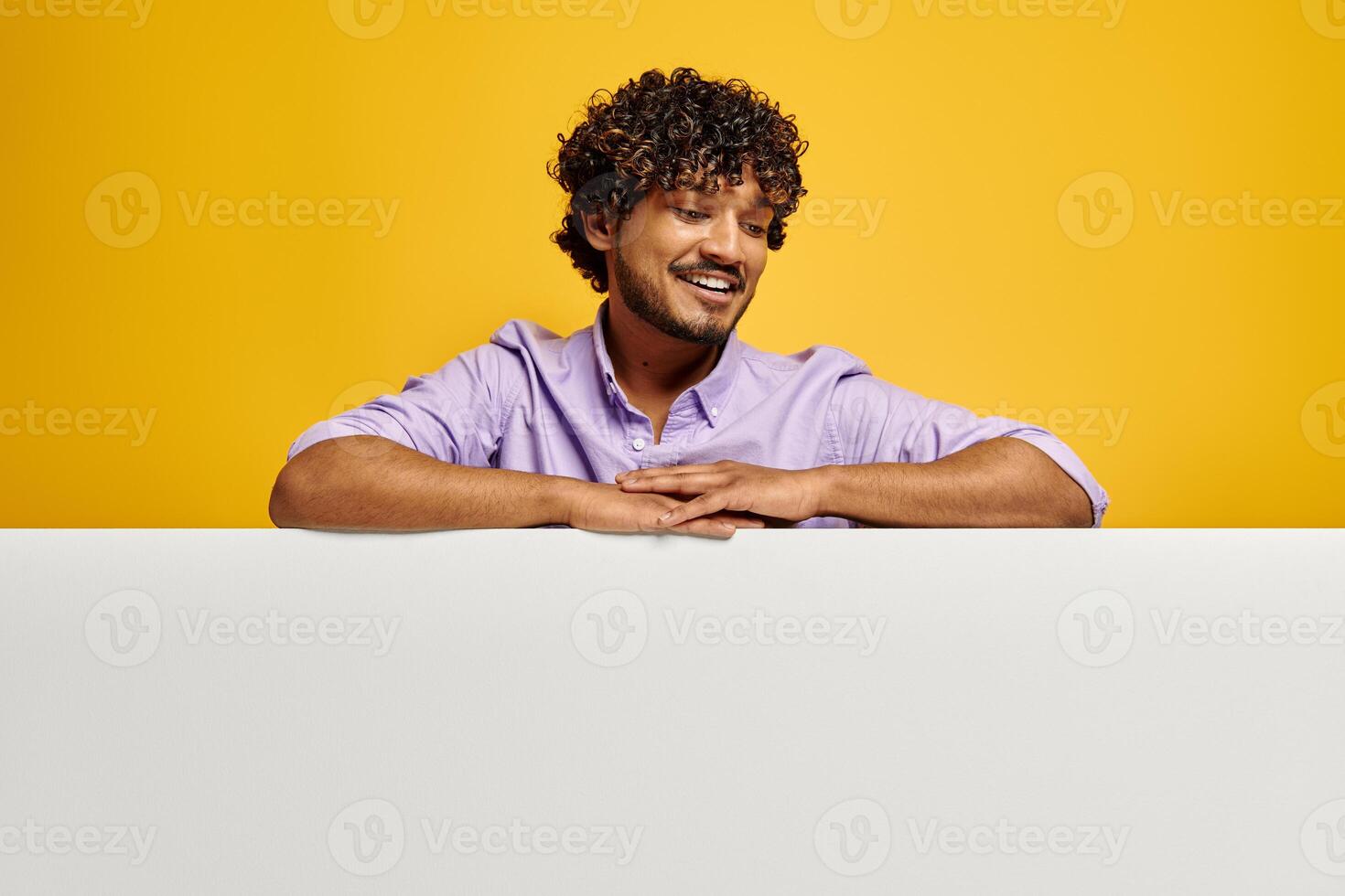 Handsome Indian man looking at the copy space and smiling against yellow background photo