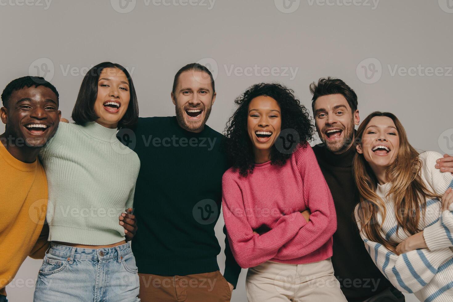 Joyful young people bonding and smiling while standing on beige background together photo