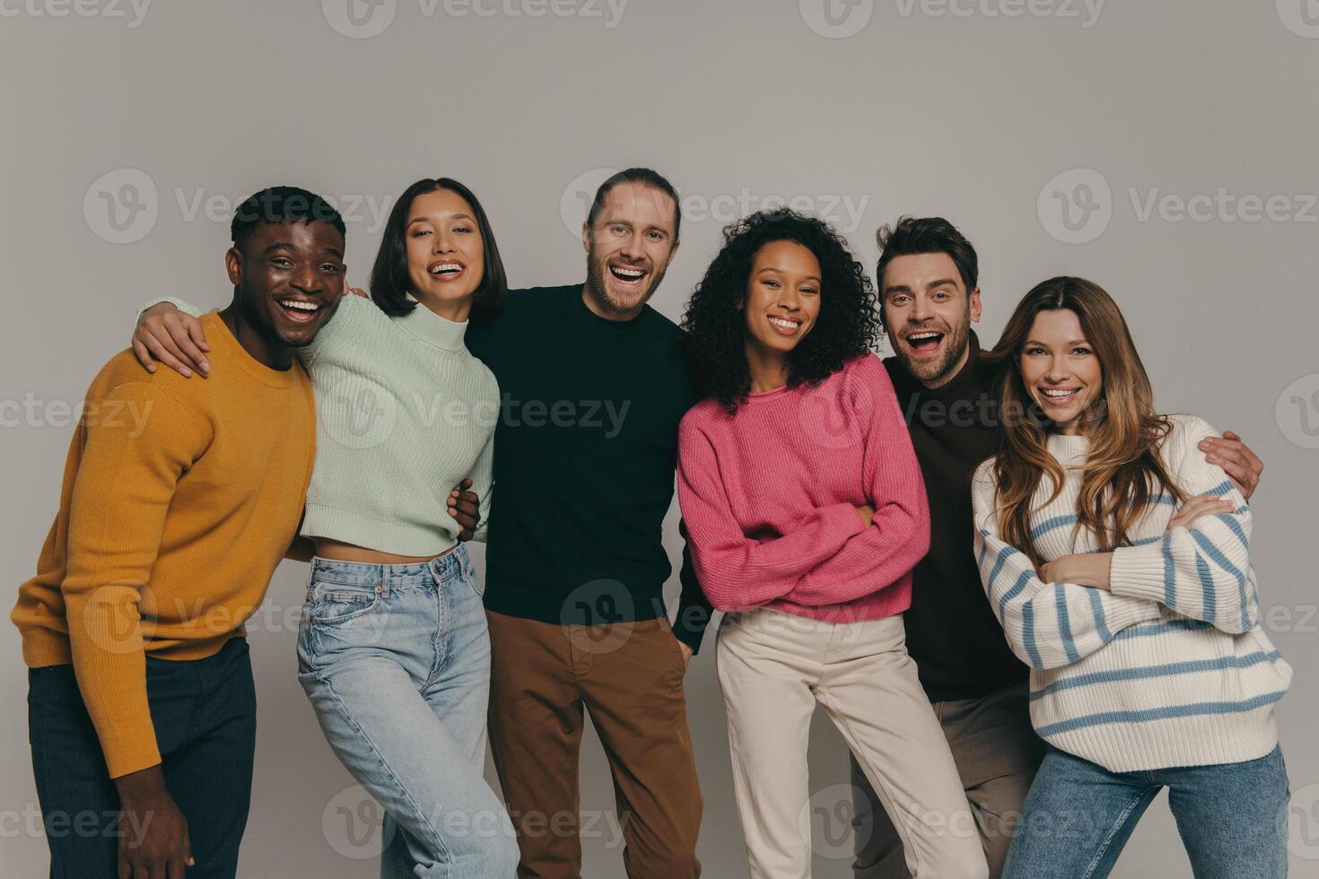 Joyful young people bonding and smiling while standing on beige background together photo