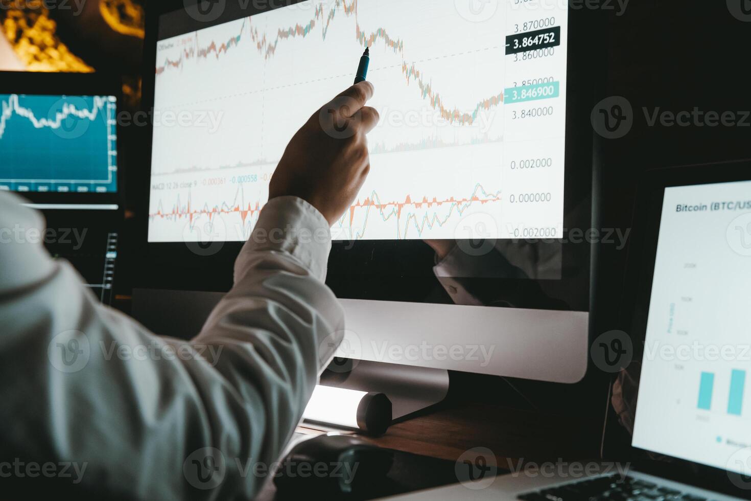 Close-up of male financial broker pointing computer monitor while analyzing stock market data in night office photo