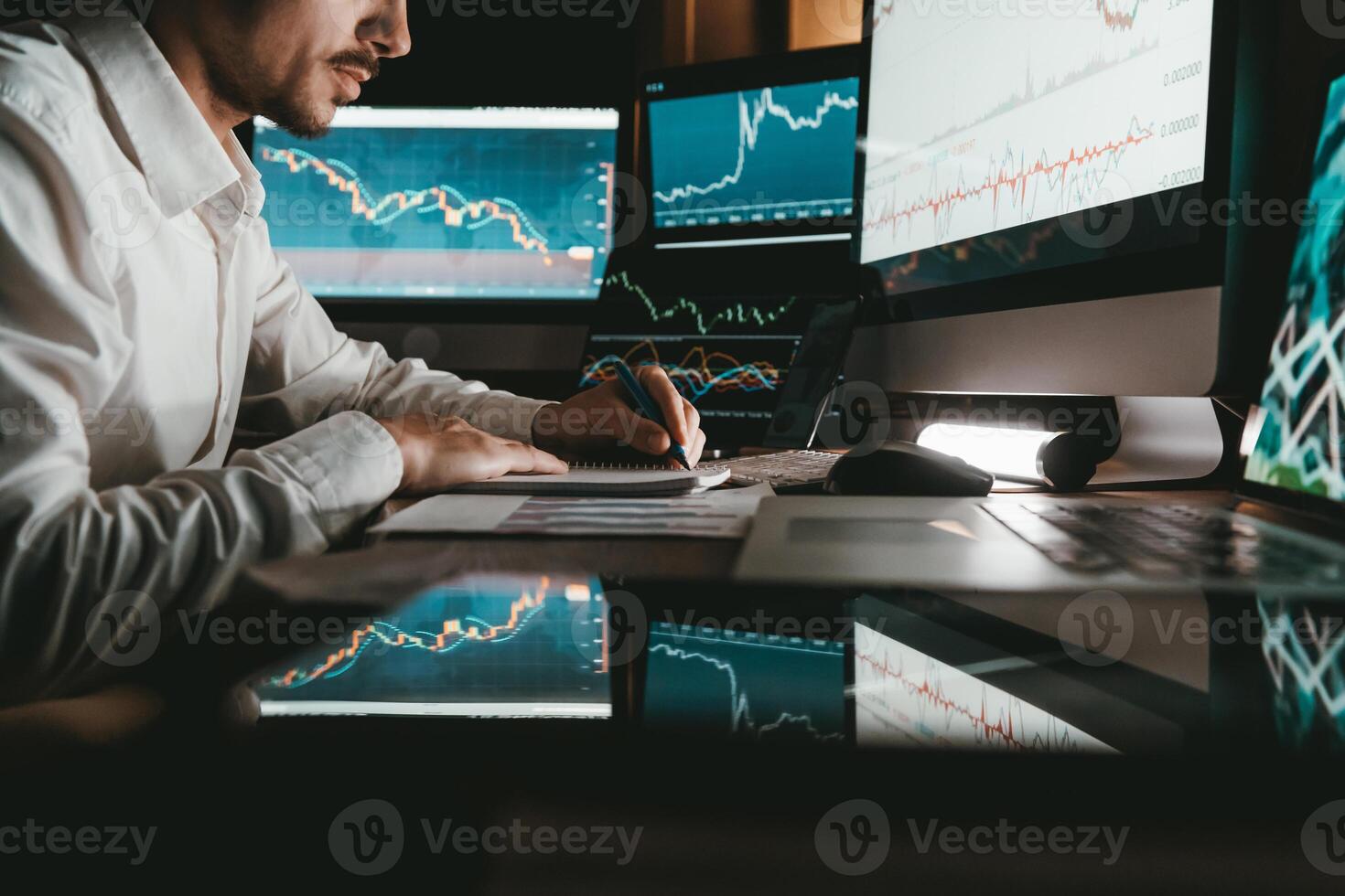 Close-up male trader analyzing stock market data while sitting at the office workstation with multiple computers photo
