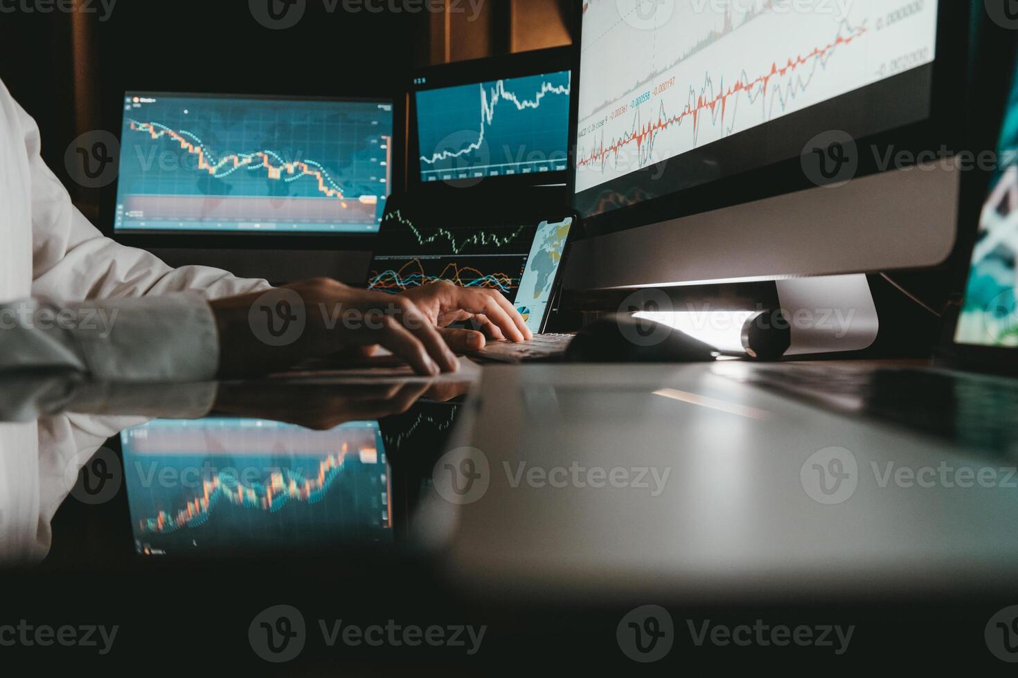 Close-up of male trader typing on computer keyboard while trading on stock market in night office photo