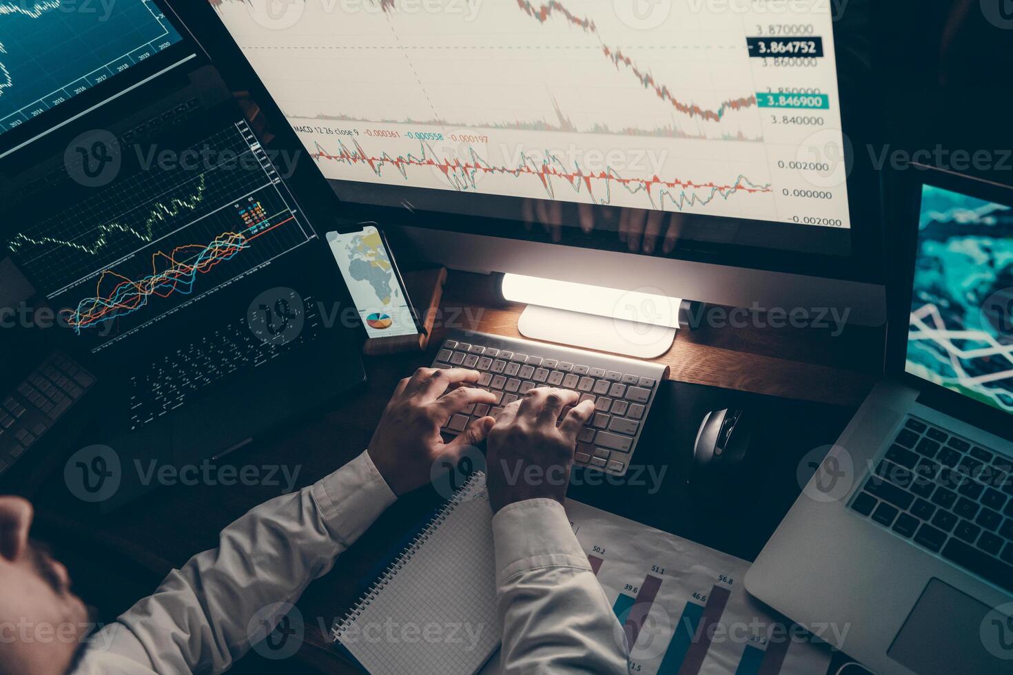 Close-up of financial broker working on computer while trading on stock market in night office photo