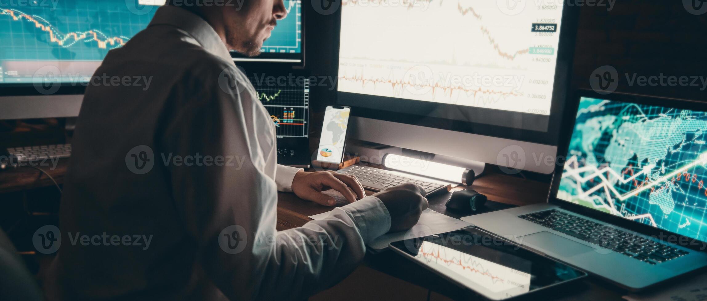 Close-up male trader analyzing stock market data while sitting at the office workstation with multiple computers photo