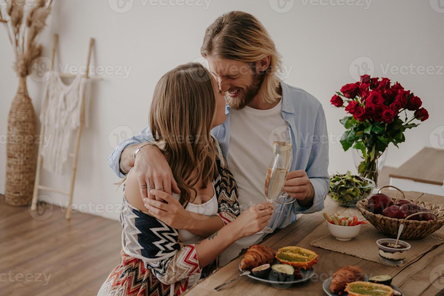Top view of young couple embracing and toasting with champagne while celebrating anniversary at home photo