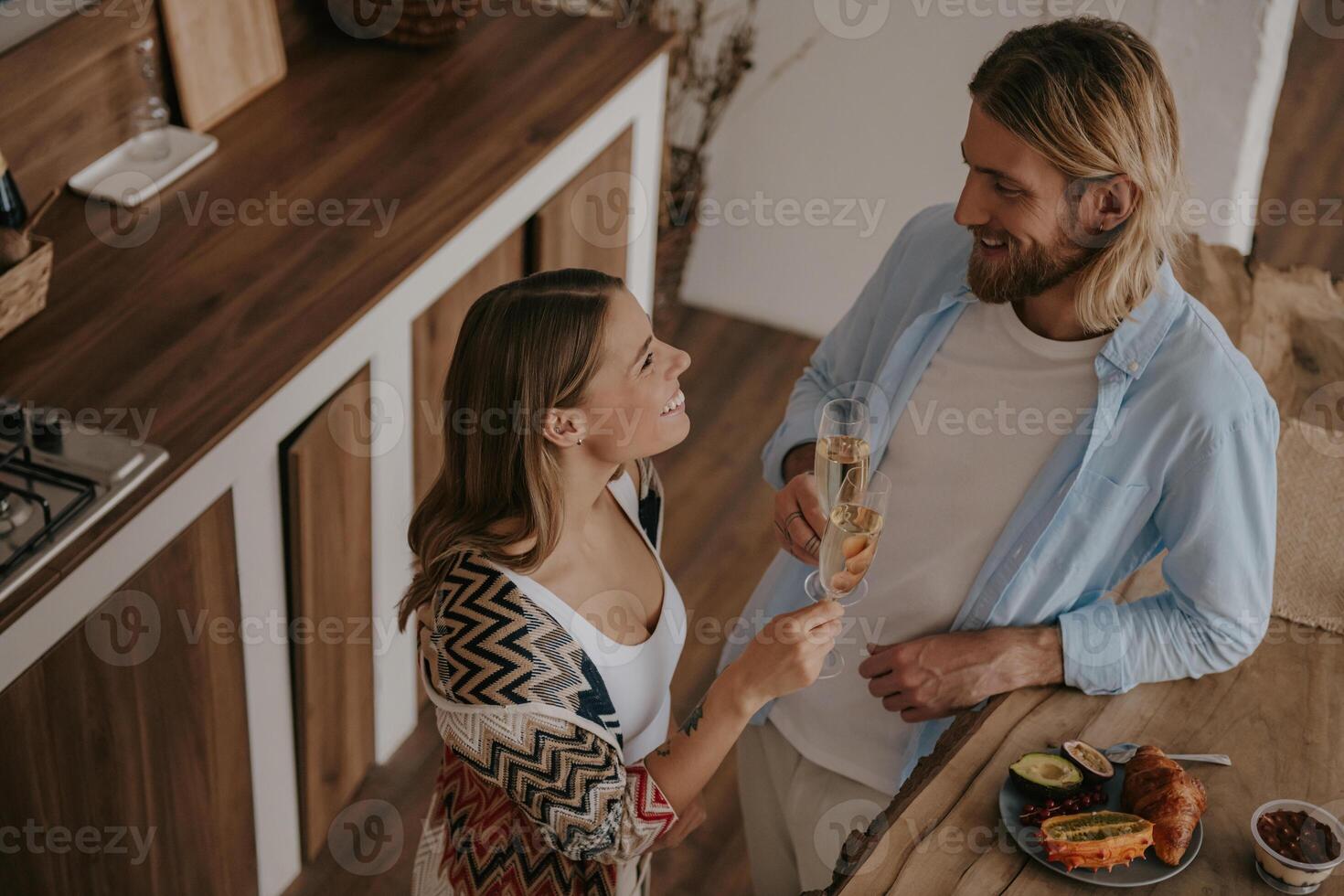 Top view of young loving couple toasting with champagne and smiling while celebrating anniversary at home photo