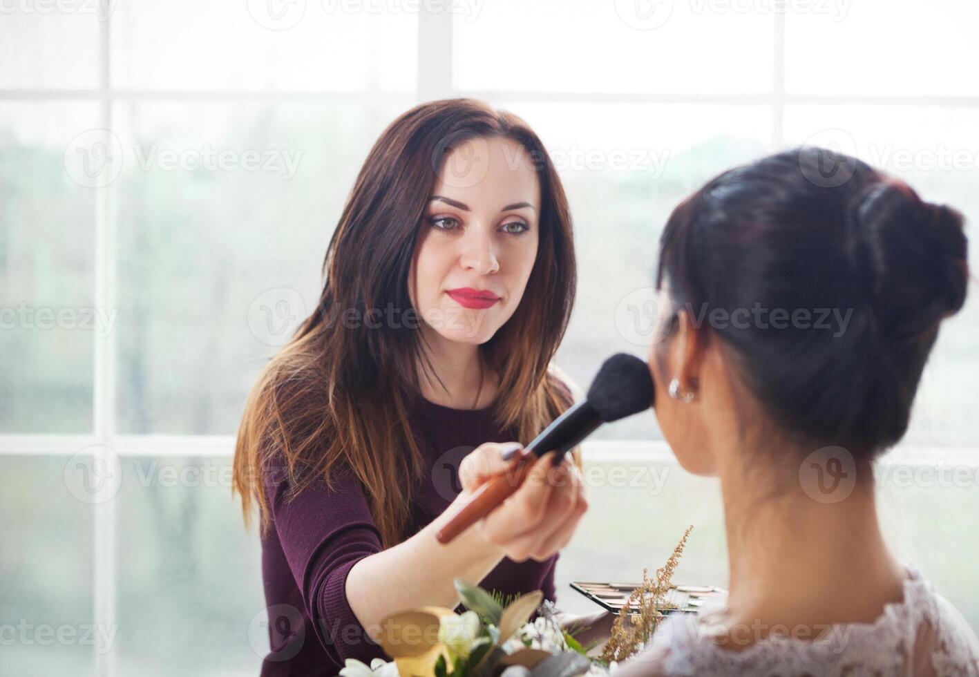 Make-up artist doing make up for young beautiful bride photo