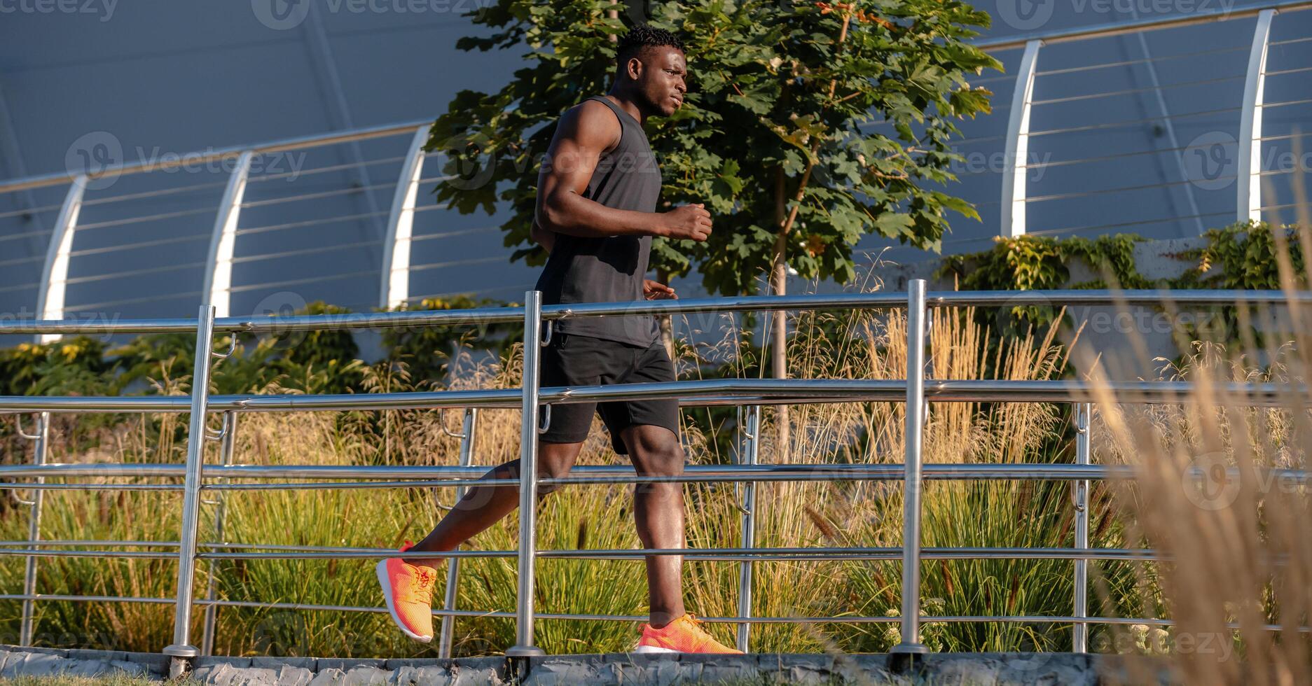 Full length of confident African athlete in sportswear looking concentrated while running outdoors photo